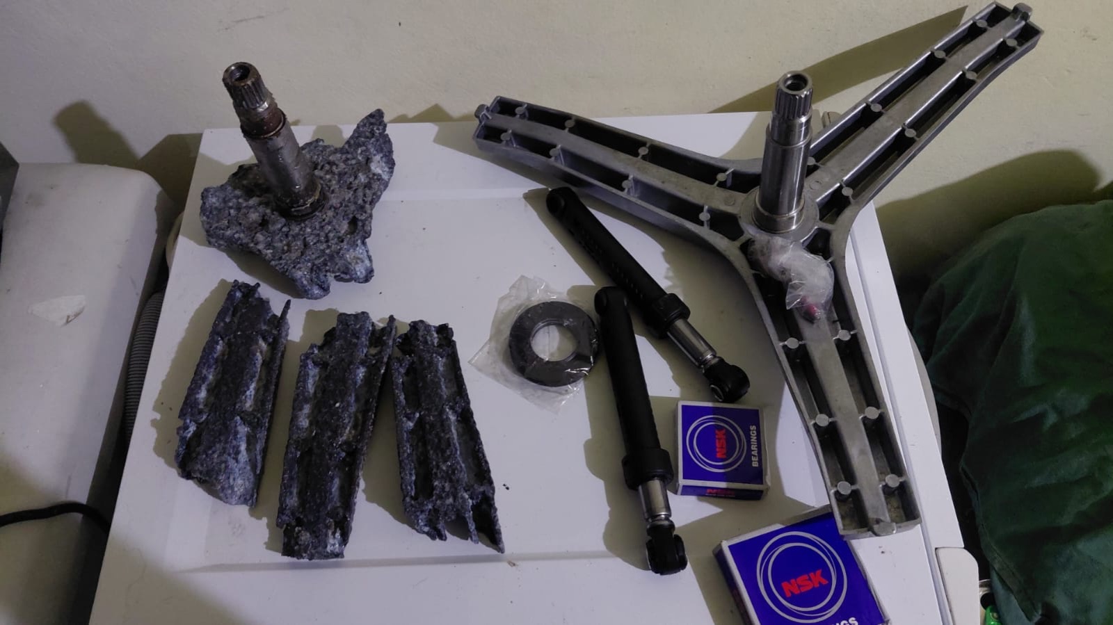 Eixo corroído ao lado de cruzeta nova, amortecedores novos e rolamentos na embalagem